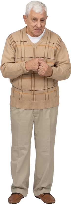 Vista frontal de um velho feliz em roupas casuais em pé com os punhos cerrados