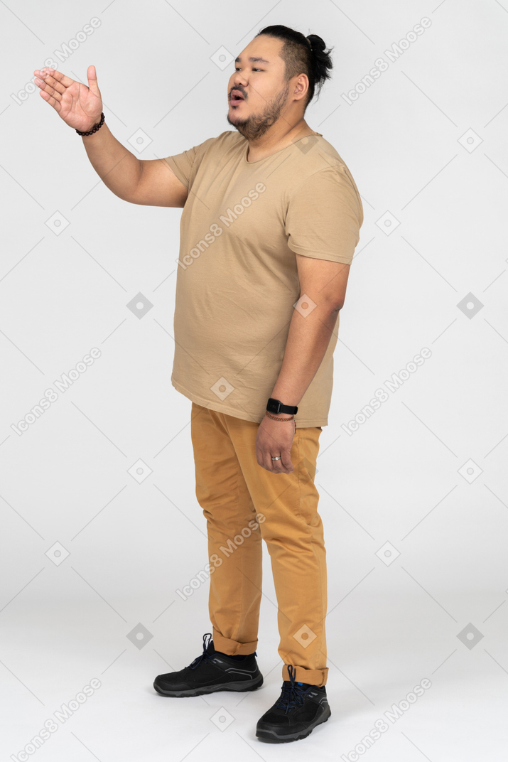 Giovane uomo asiatico gesticolando lateralmente alla telecamera