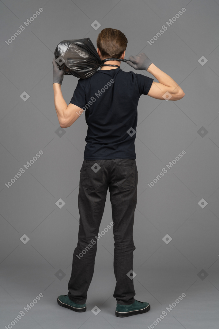 A young man holding a trash bag behind his head