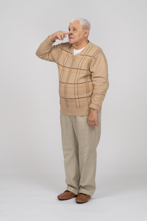 Vue de face d'un vieil homme en vêtements décontractés touchant le nez