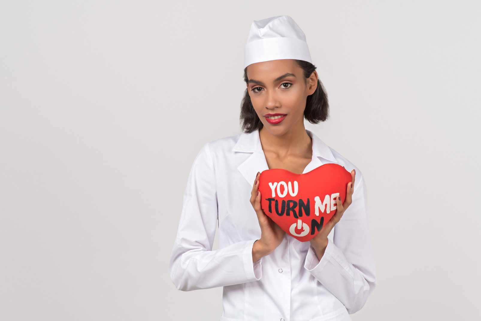 Attractive young female doctor holding a toy heart