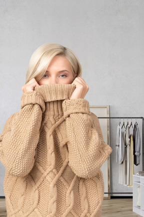 A woman pulling her sweater over her face