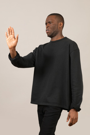 Hombre frunciendo el ceño y mostrando un gesto de parada con la palma