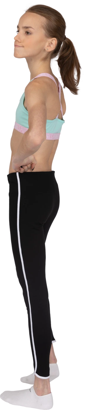 Three-quarter back view of a displeased teen girl in sportswear putting hands on hips and squeezing lips