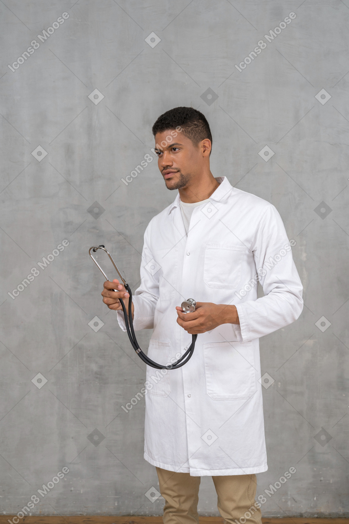 Männlicher arzt, der ein stethoskop hält