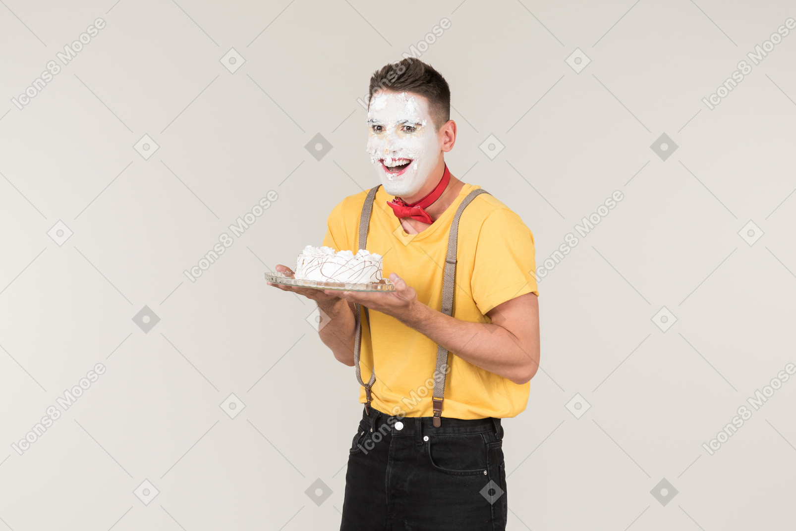 Male clown with cake cream on his face holding a cake