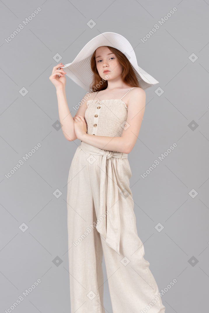 Teenage girl wearing big white hat and holding her hands in a pose