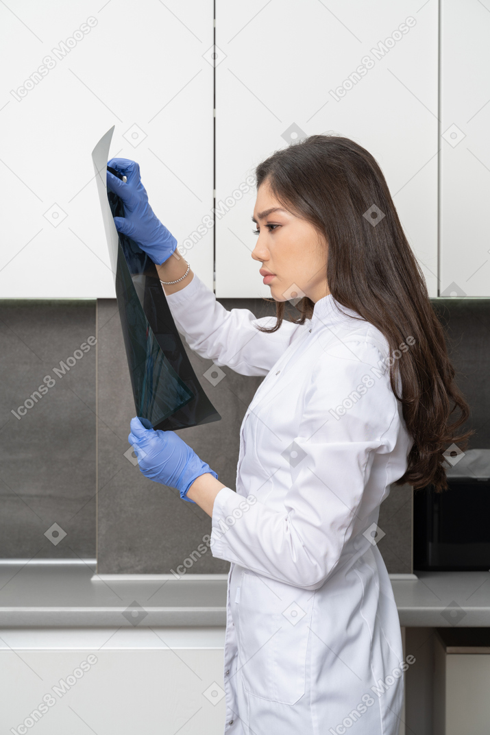Side view of a thoughtful female doctor analyzing x-ray image