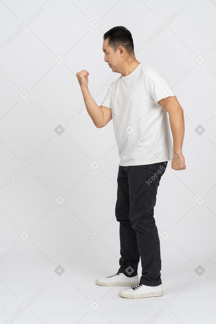 Side view of a man in casual clothes threatening someone with fist