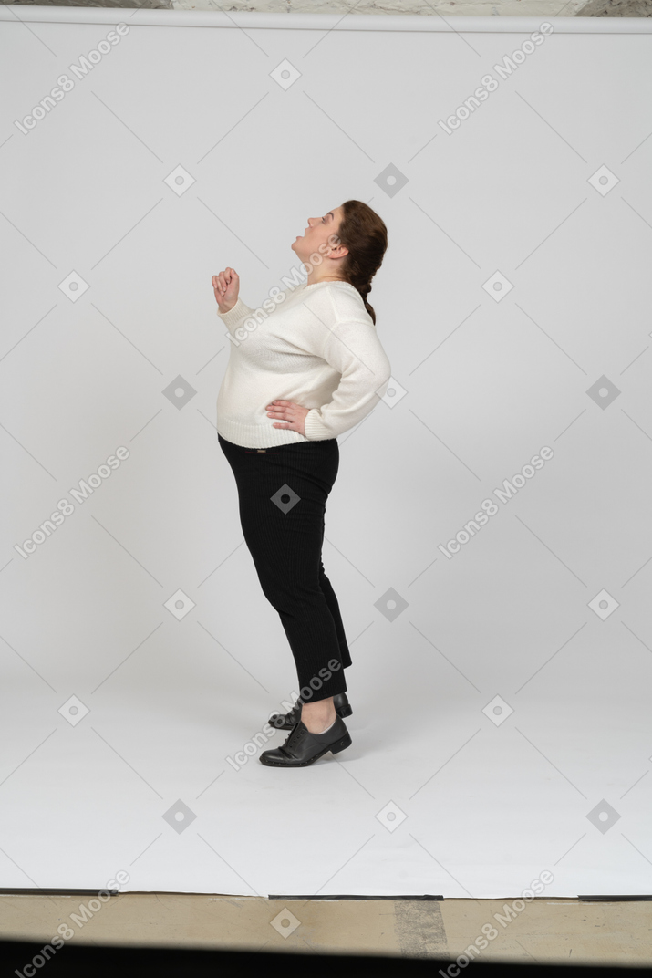 Vista lateral de una mujer regordeta en ropa casual mirando hacia arriba