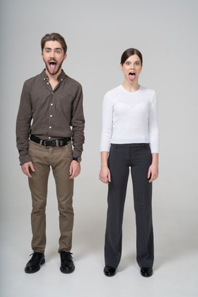一对疯狂的年轻夫妇在显示舌头的办公室服装的前视图