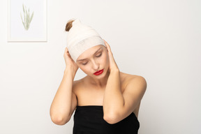 Mujer joven sosteniendo su cabeza vendada