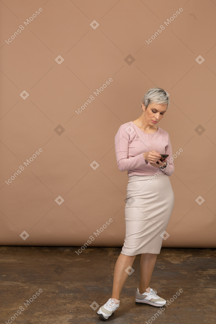 一个穿着休闲服的女人正在查看她的手机的前视图