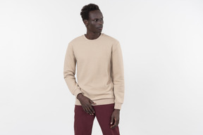 A young black man in a grey sweater standing alone on the white background