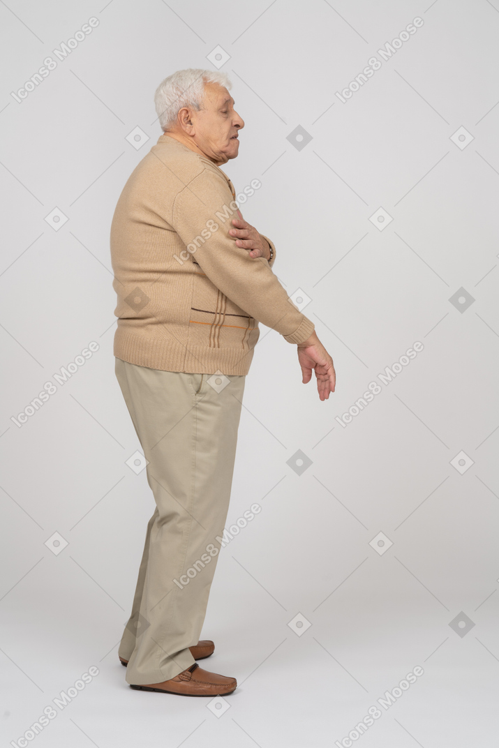 Side view of an old man standing with hand on arm