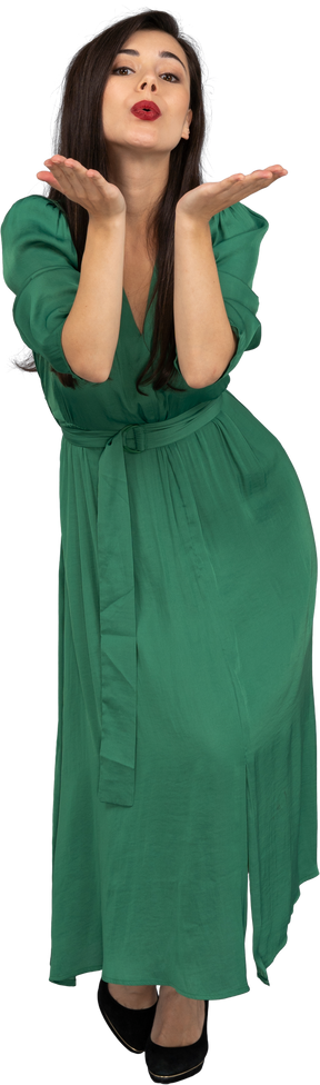 Vista frontal de uma jovem de vestido verde enviando um beijo no ar