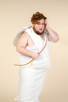 Worried big guy dressed as a cupid holding bow