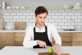A man cutting an apple on a cutting board