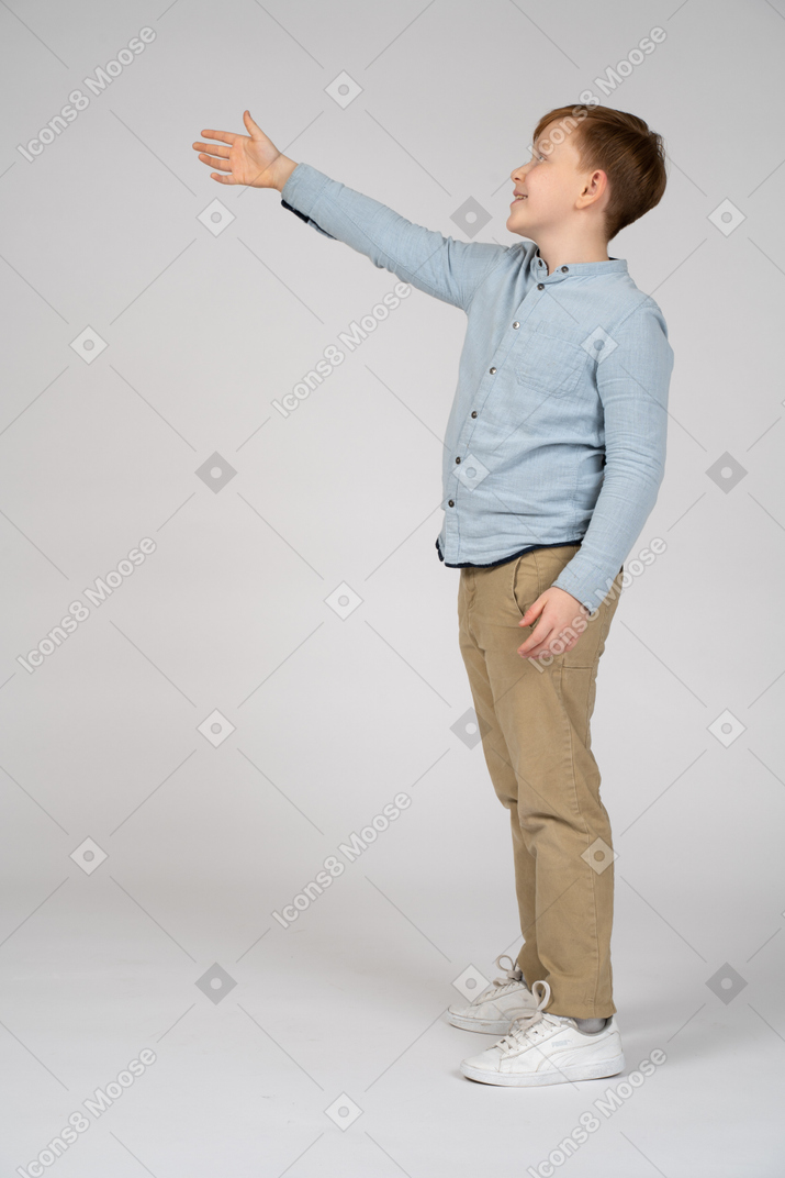 Side view of a cheerful boy pointing up with hand