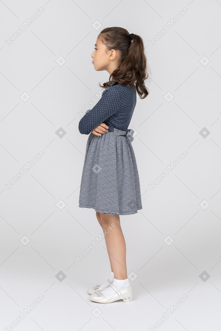 Vista lateral de una niña haciendo pucheros con las manos cruzadas