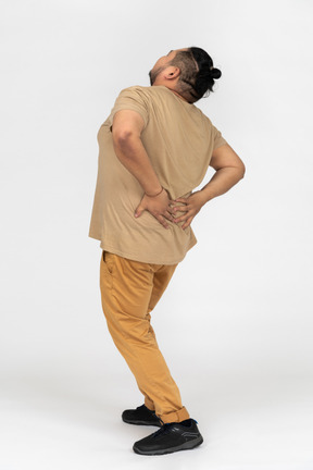 Asian man suffering from backache and holding his lower back with both hands