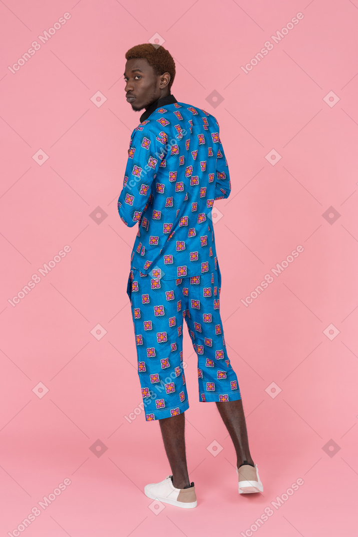Black man in blue pajamas standing on the pink background