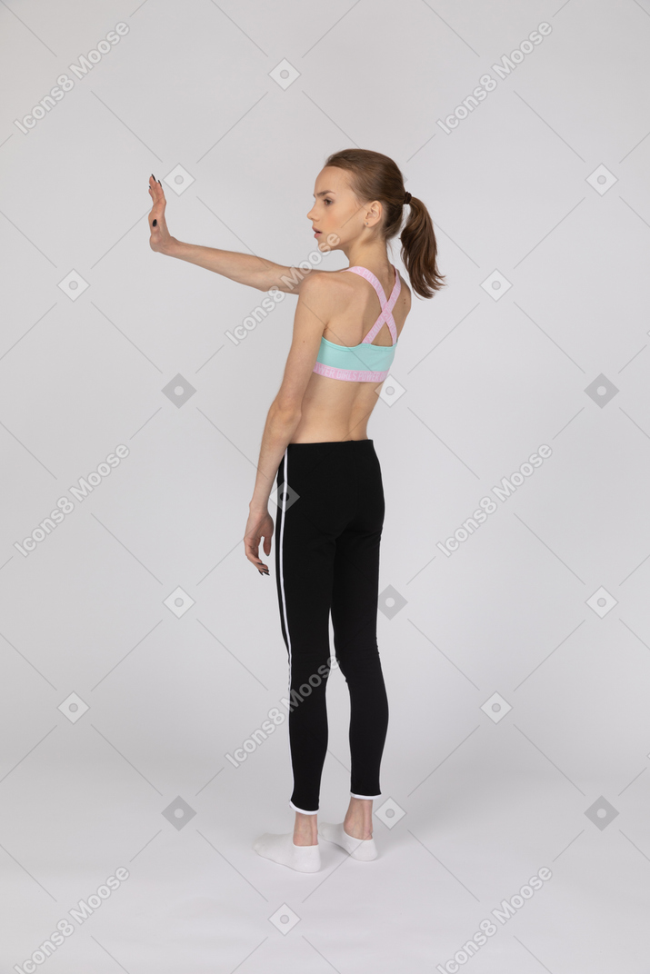 Девушка-подросток в спортивной одежде протягивает руку