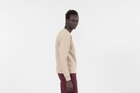 A young black man in a grey sweater standing alone on the white background