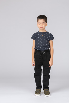 Вид спереди симпатичного мальчика в повседневной одежде, стоящего с закрытыми глазами