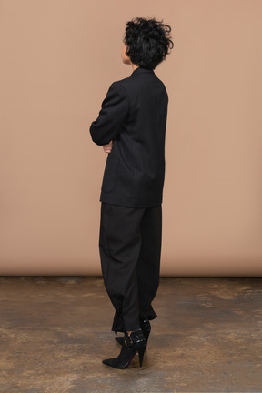 Vista de tres cuartos de una empresaria vestida con traje negro cruzando las manos