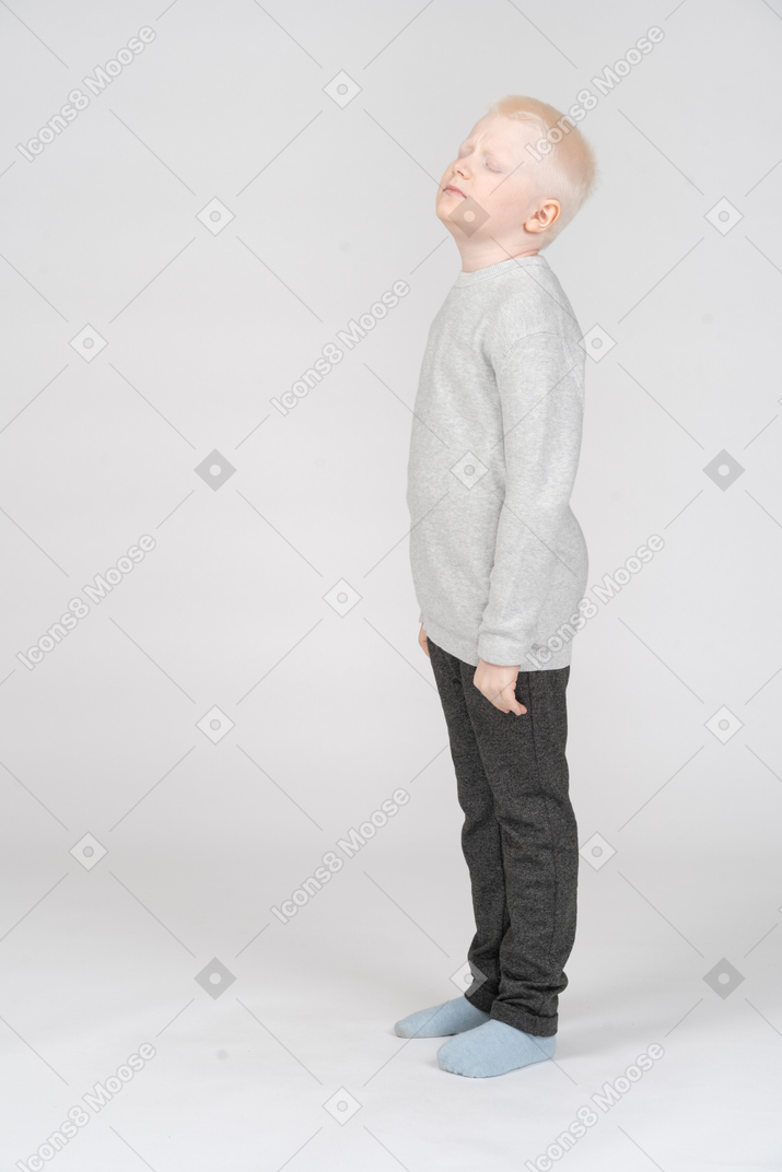 Full-length of a miserable little boy raising head with his eyes closed