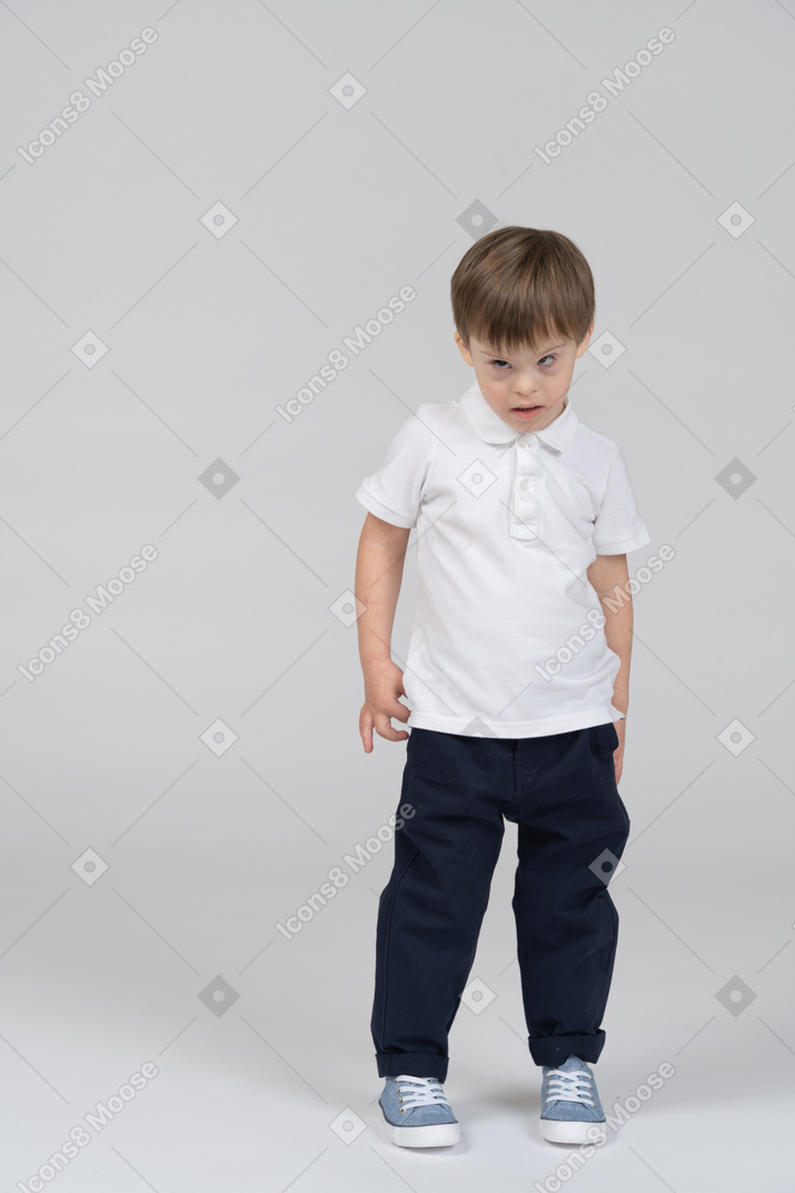 Маленький мальчик стоит с руками по бокам и смотрит исподлобья