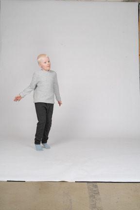 Vista frontal de um menino em roupas casuais em pé na ponta dos pés