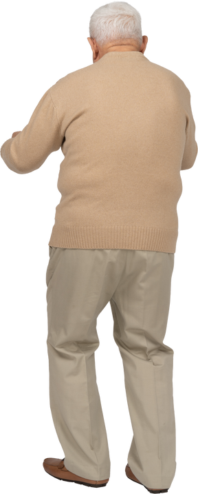 Вид сзади на старика в повседневной одежде, стоящего со сжатыми кулаками