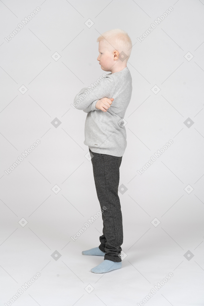 Vista lateral de um menino com as mãos cruzadas