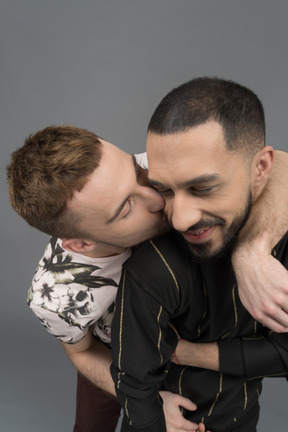 Young man kissing his boyfriend from behind