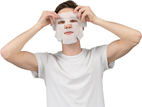 Vue de face d'un jeune homme mettant un masque facial
