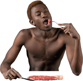 Vista frontal de un joven afro comiendo carne cruda