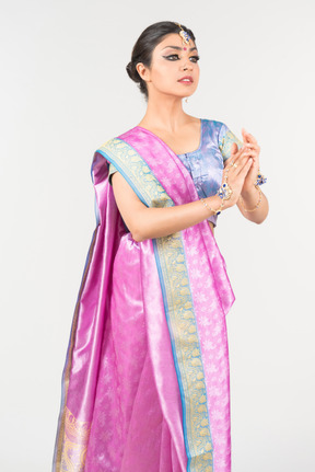 Jovem mulher indiana em pé de sari roxo com as mãos postas