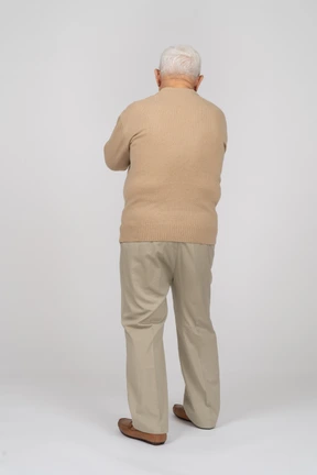 Rear view of an old man in casual clothes walking