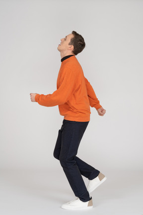 Junger mann im orange sweatshirt springen