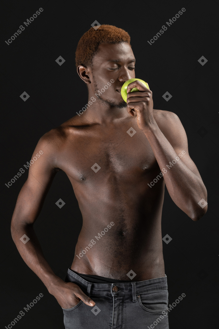 Close-up an african man smelling a green apple in the dark