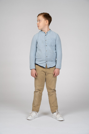 Vista frontal del niño con ropa informal mirando a un lado