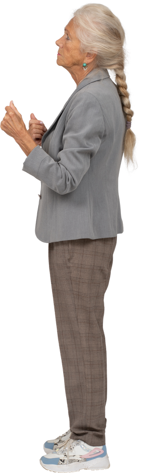 Vista lateral de uma senhora idosa de terno em pé com os punhos cerrados