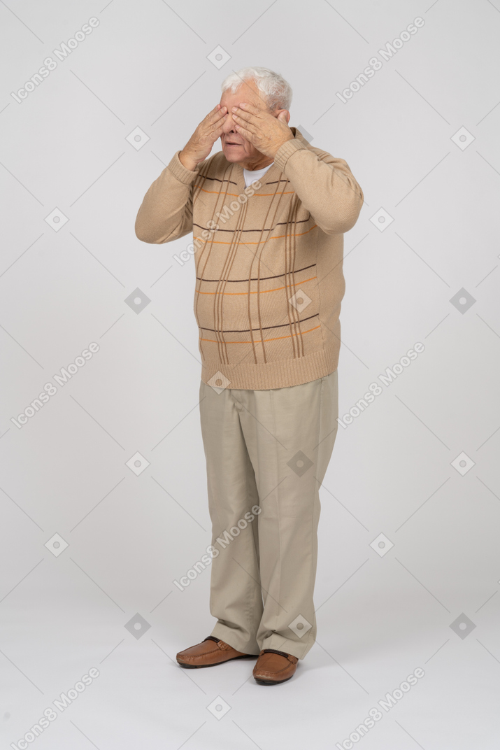 Vorderansicht eines alten mannes in freizeitkleidung, der die augen mit den händen bedeckt