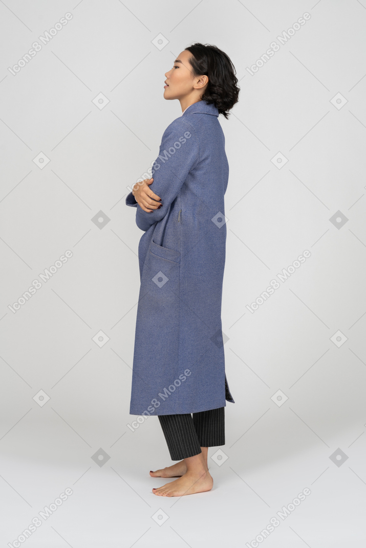 両手を自分に巻き付けたコートを着た女性の側面図