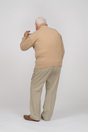 Rear view of an old man in casual clothes showing size of something