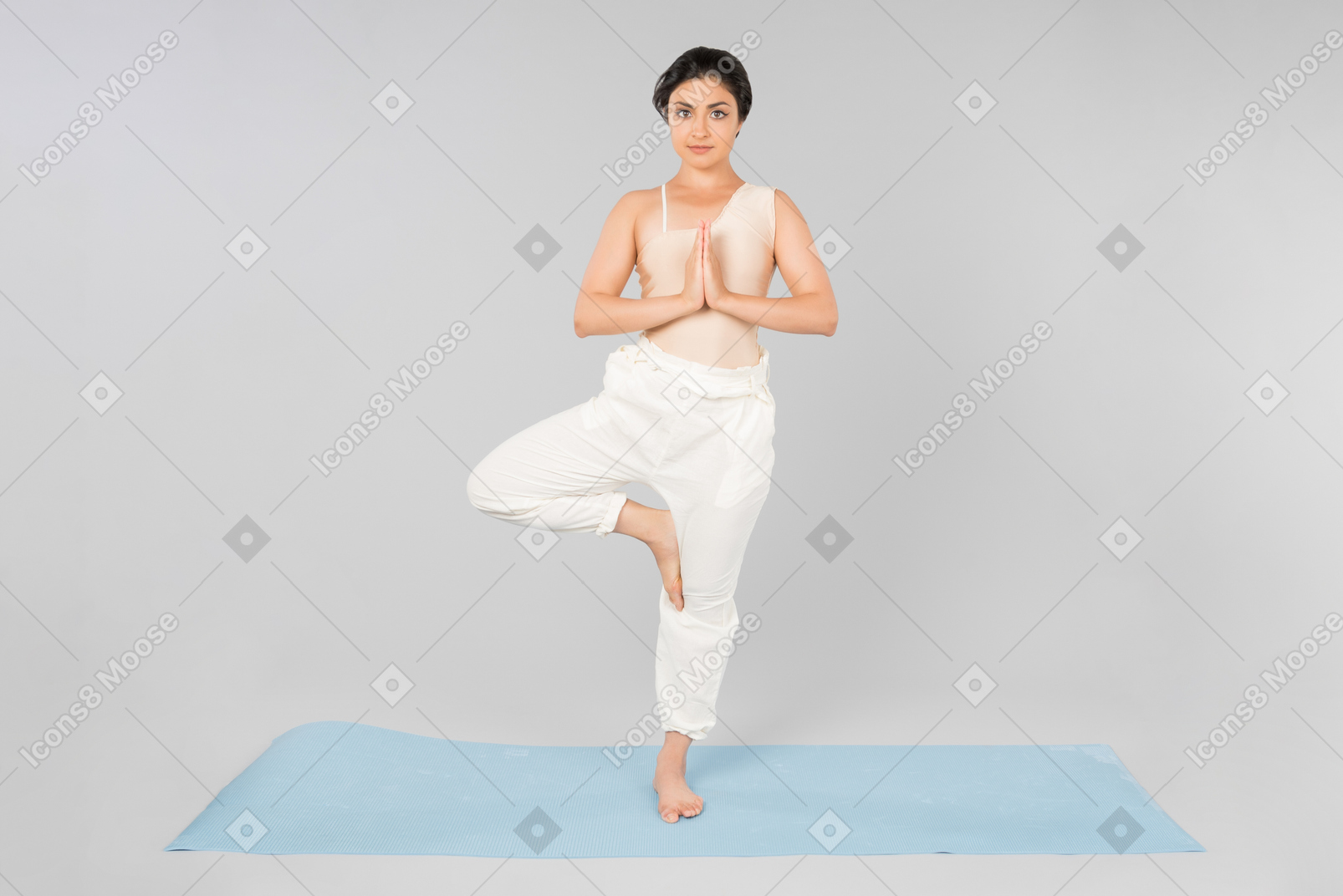 Young indian woman standing in tree position on yoga mat