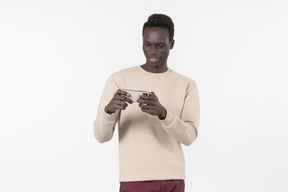 Junger schwarzer mann in einem grauen pullover mit seinem smartphone