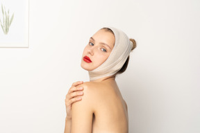 Woman with bandaged head touching her shoulder